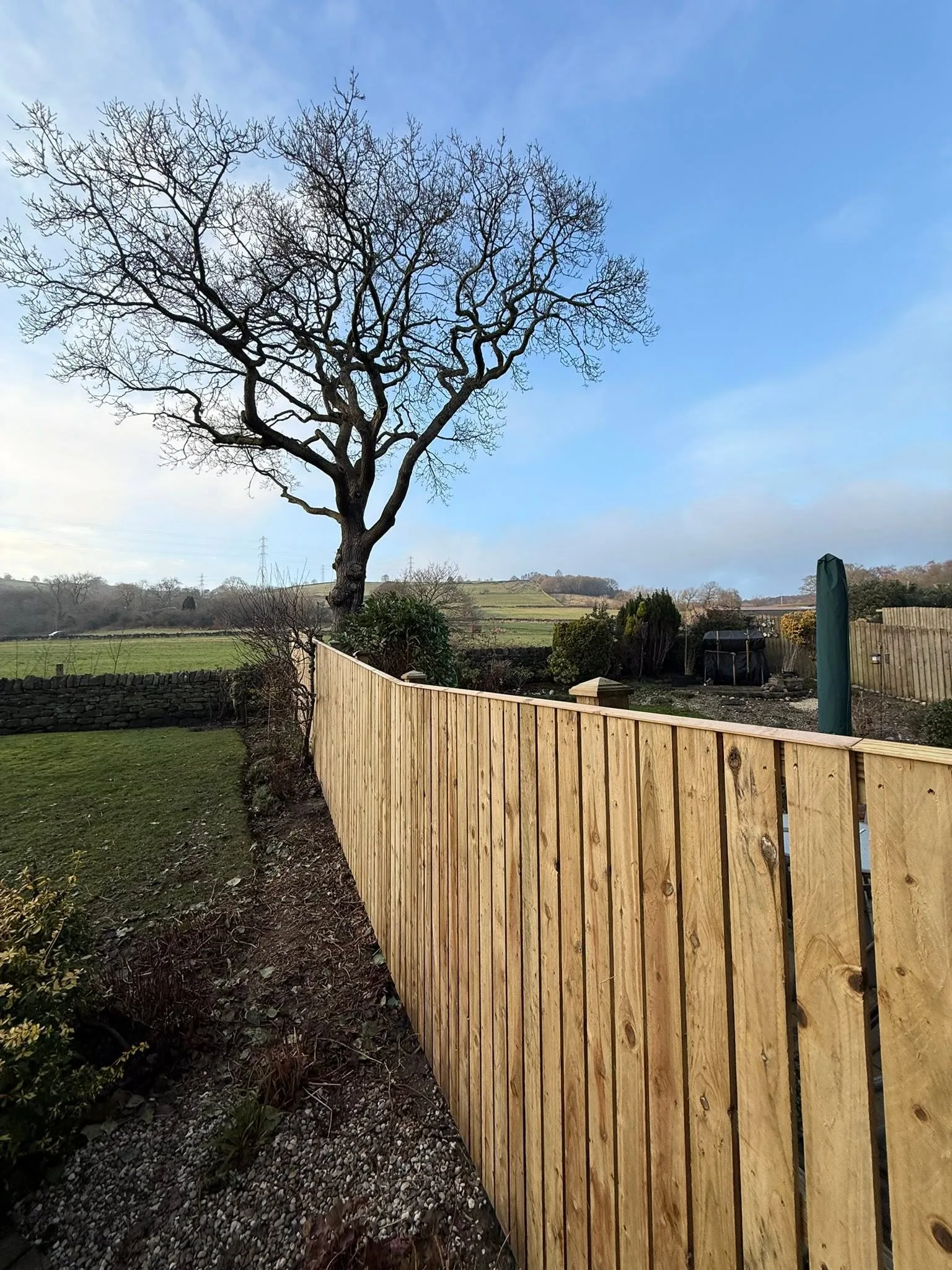 Finished timber fencing beside lawn and open countryside